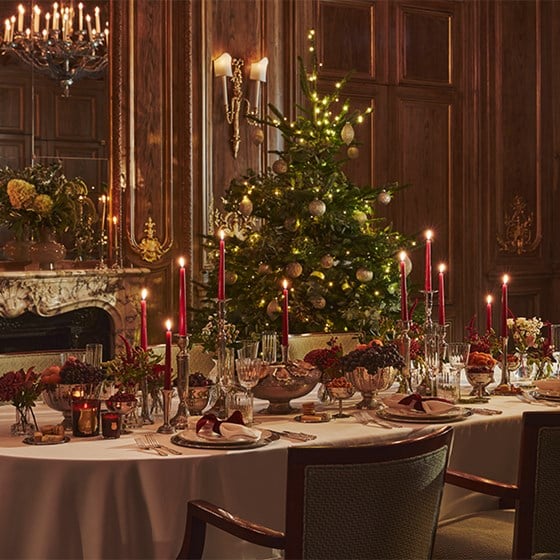 A beautifully arranged festive table, with a decorated Christmas tree behind it.
