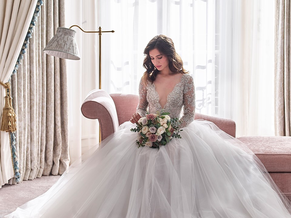 A beautiful bride sitting and posing with a bouquet in her hands in the romantic atmosphere of Claridge's Hotel.