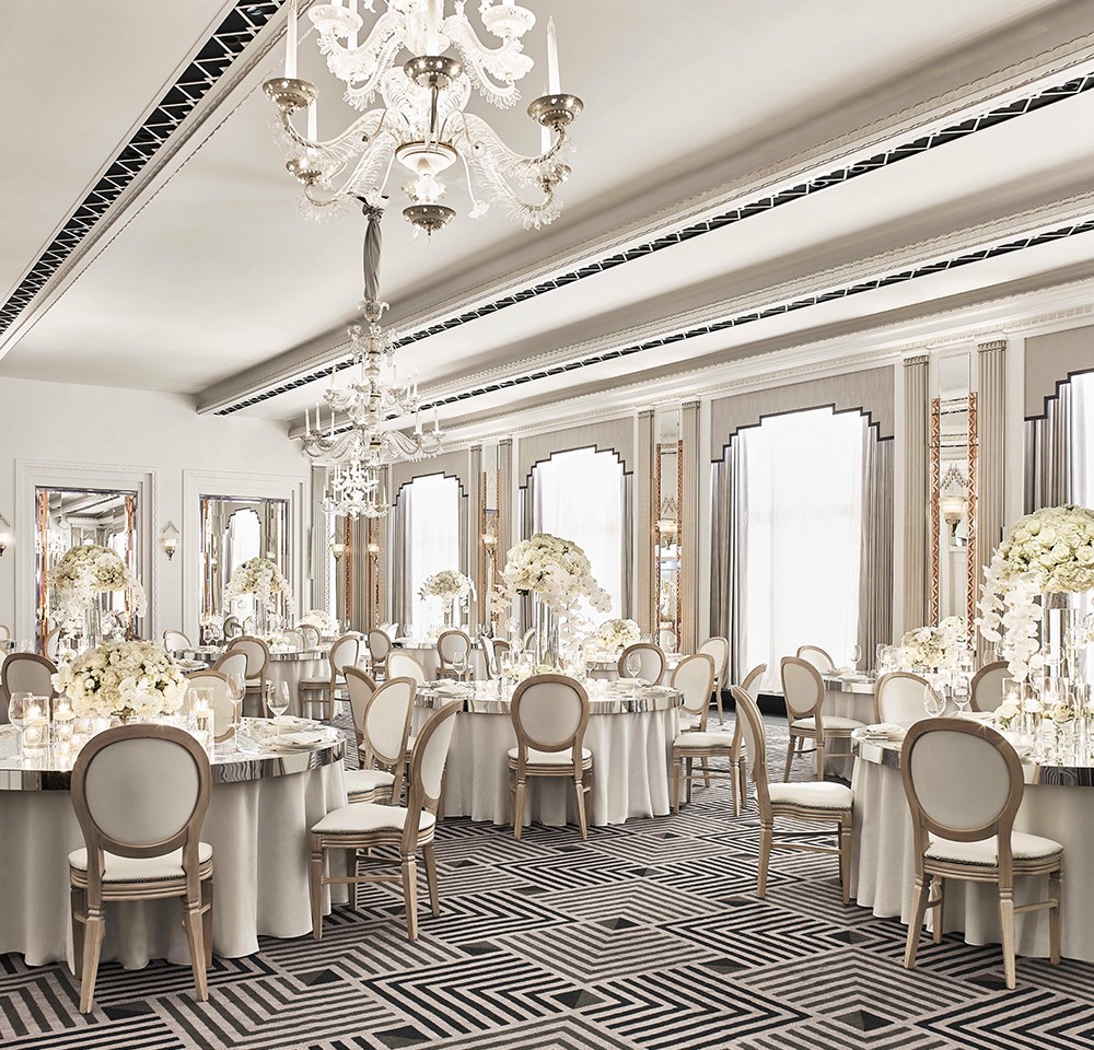 Chairs and tables are lavishly decorated with floral arrangements in the elegant Art Deco Ballroom of Claridge's Hotel.