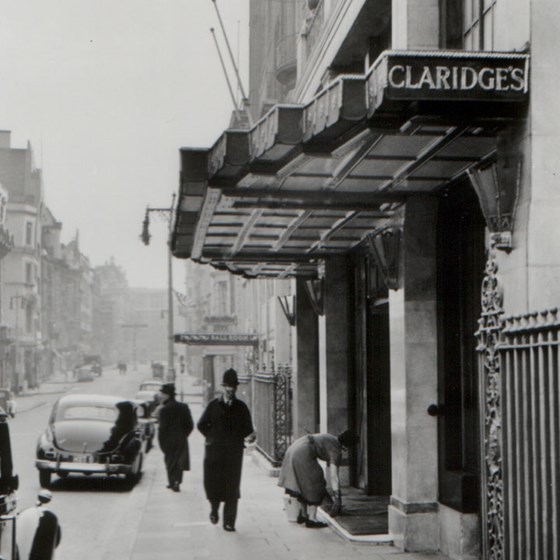 A black and white photo in front of Claridge's Hotel and the passers-by at that time as part of history.