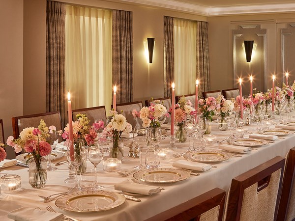table laid with lots of small vases filled with pink and white flowers, and pink candles lit up the table