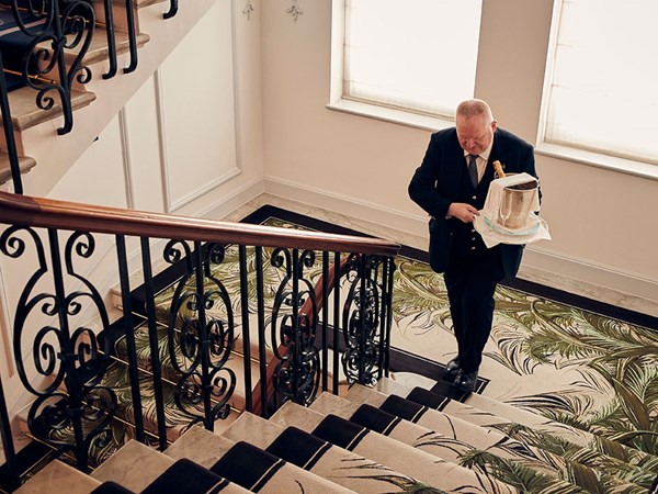 butler walking up stairs holding bucket of champagne and ice