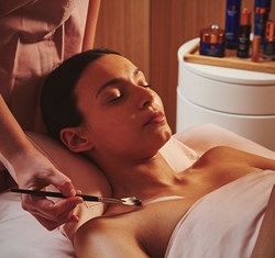A view of a girl enjoying a gentle treatment from Claridge's Spa, with a wellness professional applying the treatment.