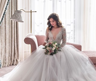 A beautiful bride sitting and posing with a bouquet in her hands in the romantic atmosphere of Claridge's Hotel.