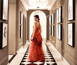 Photograph of a graceful woman posing in a red dress in the corridor of Claridge's Hotel.
