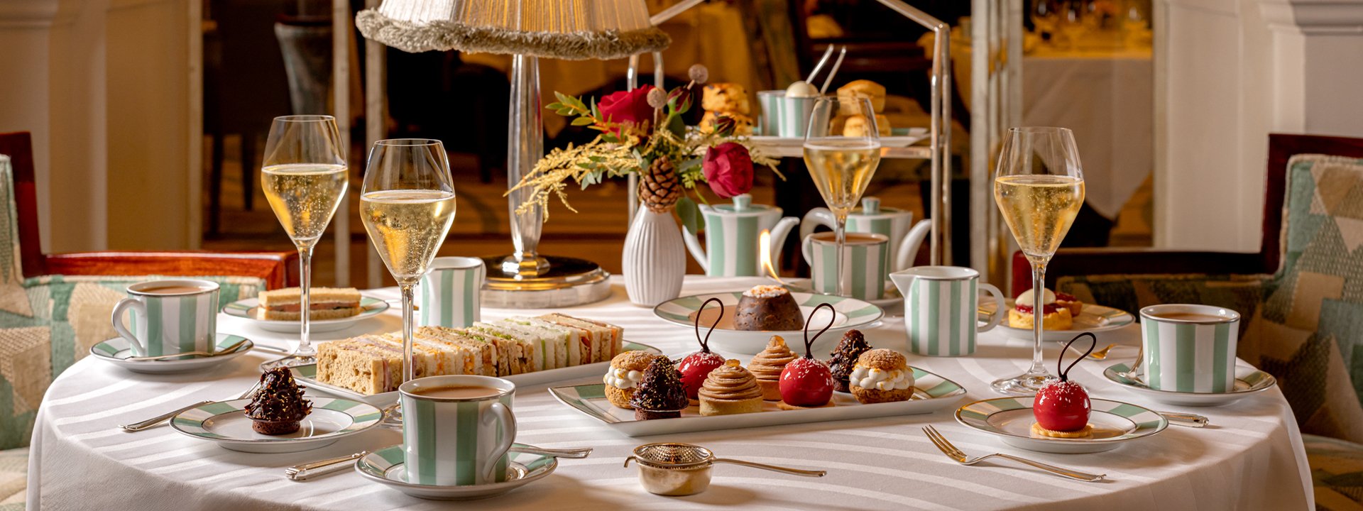 The first image showcases a refined afternoon tea spread with an assortment of elegant sandwiches and intricate pastries, paired with a glass of Champagne on Claridge’s signature green and white striped china.