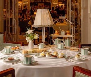 A refined afternoon tea setting at Claridge’s, with an elegant arrangement of pastries, freshly brewed tea, delicate finger sandwiches, and classic scones, complemented by the sophisticated ambiance of the tea lounge.
