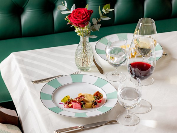 Valentine's Day menu at The Foyer and Reading Room with a dish in a plate, a rose in a vase and wine in glasses.