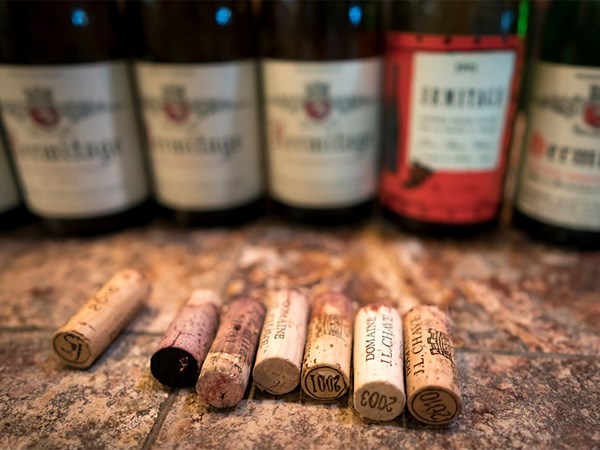 Several wine corks lined up on a surface with their respective bottles in the background, slightly out of focus. The corks and bottles suggest a tasting session featuring vintage wines.