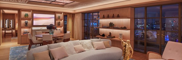 living room of penthouse with dining table in the background with a window showing the London city skyline at night