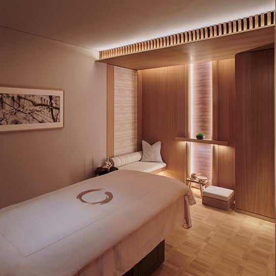 A treatment room at Claridge's Spa. In the foreground there is a massage table and in the background the items for the treatments are displayed.