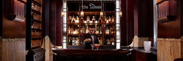 A sophisticated Art Deco bar scene at The Fumoir, with a bartender preparing a classic cocktail.