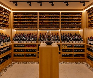 A collection of wine and champagne in the background, with a decanter in the middle at Claridge's Wine Cellar.